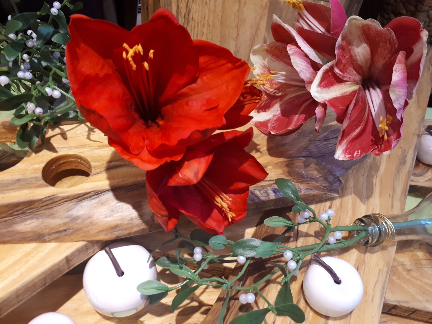 rote künstliche Amaryllis Blüten auf Holzbrett